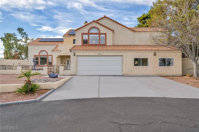 mediterranean / spanish-style house with solar panels and a garage