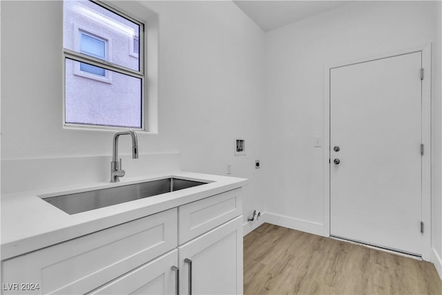 clothes washing area with cabinets, sink, washer hookup, hookup for an electric dryer, and light hardwood / wood-style floors