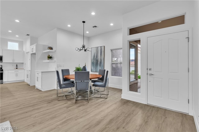 dining space with light wood-type flooring and a chandelier