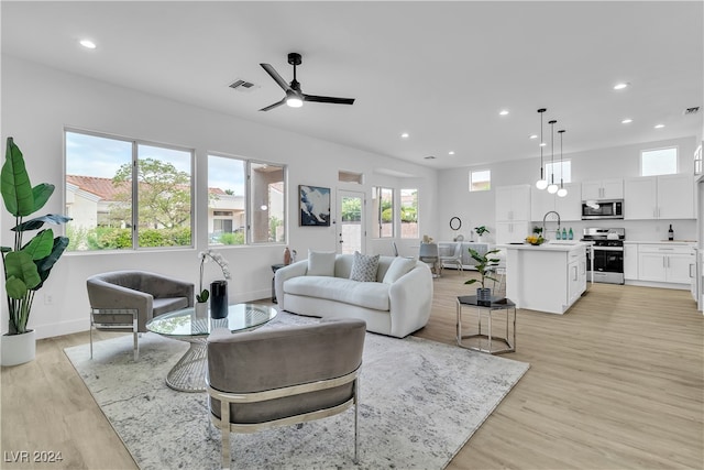 living room featuring ceiling fan, sink, and light hardwood / wood-style floors