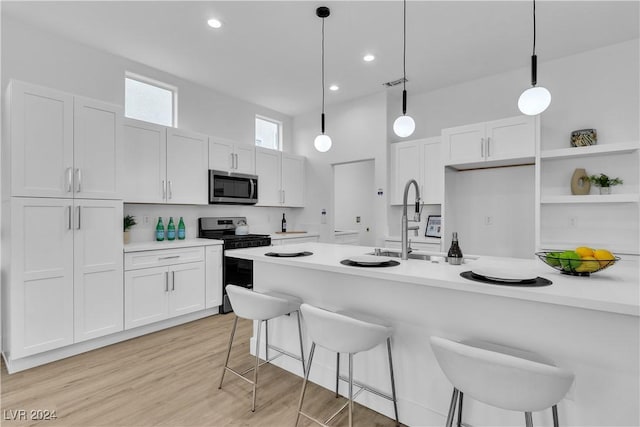 kitchen featuring electric stove, light hardwood / wood-style flooring, white cabinets, and hanging light fixtures