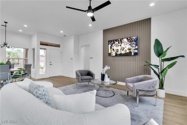 living room featuring ceiling fan with notable chandelier and light hardwood / wood-style floors