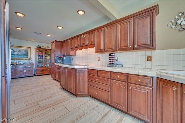 kitchen with backsplash, tile countertops, and light wood-type flooring