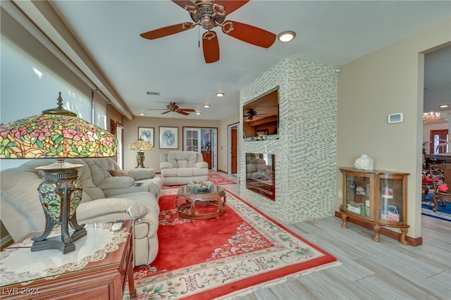 living room featuring a fireplace, light hardwood / wood-style floors, and ceiling fan