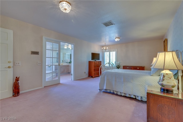 bedroom with ensuite bath, carpet floors, and an inviting chandelier