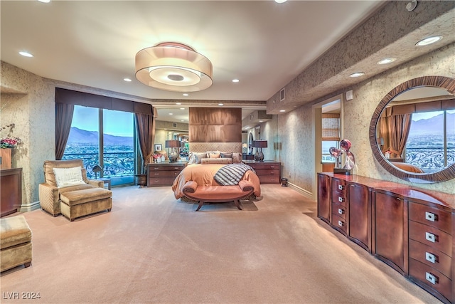 bedroom with a mountain view, light carpet, and multiple windows