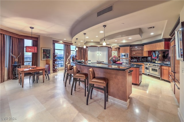 kitchen featuring a breakfast bar, sink, hanging light fixtures, an island with sink, and appliances with stainless steel finishes