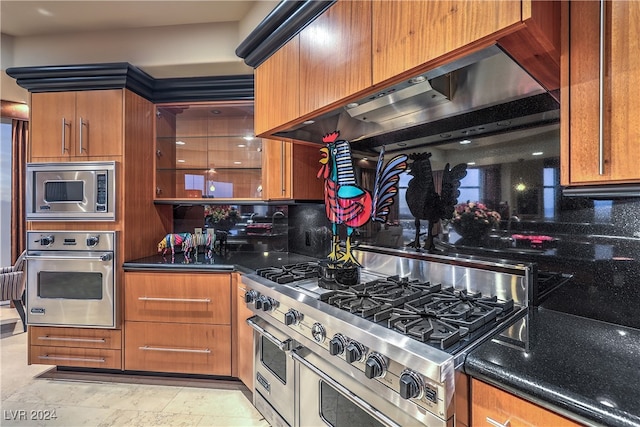 kitchen with ventilation hood, stainless steel appliances, and dark stone counters