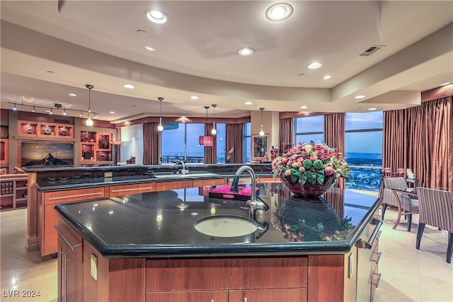 kitchen featuring a large island, sink, hanging light fixtures, and dark stone counters