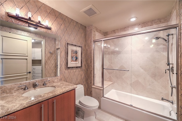 full bathroom featuring toilet, vanity, tile walls, and combined bath / shower with glass door