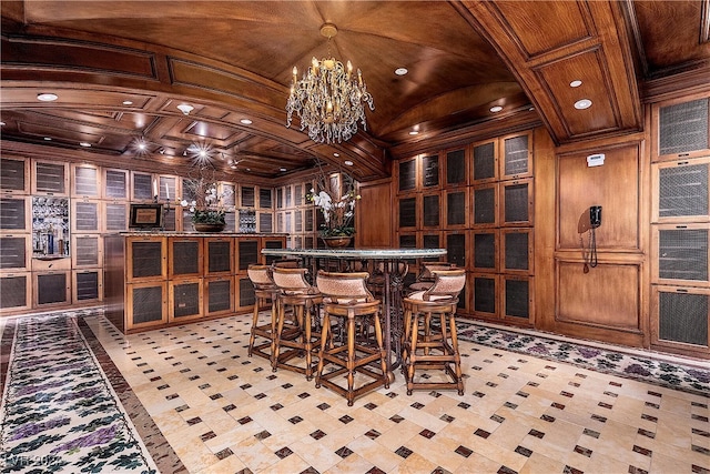 wine room with wood ceiling, vaulted ceiling, a notable chandelier, bar, and wood walls