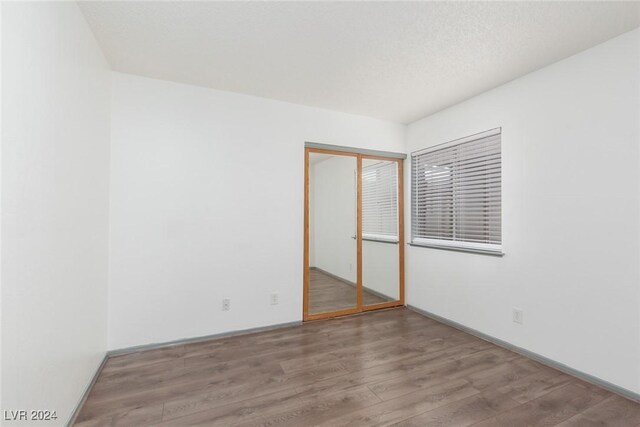 unfurnished bedroom with wood-type flooring, a textured ceiling, and a closet