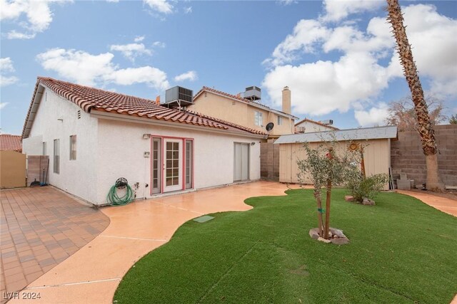 back of property featuring a patio, a yard, central air condition unit, and a shed