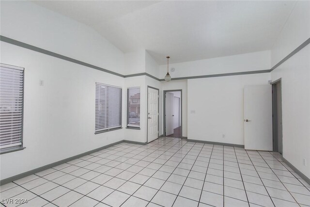 spare room with vaulted ceiling and light tile patterned floors