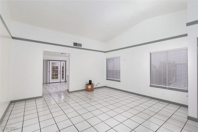 empty room with french doors, vaulted ceiling, and light tile patterned floors