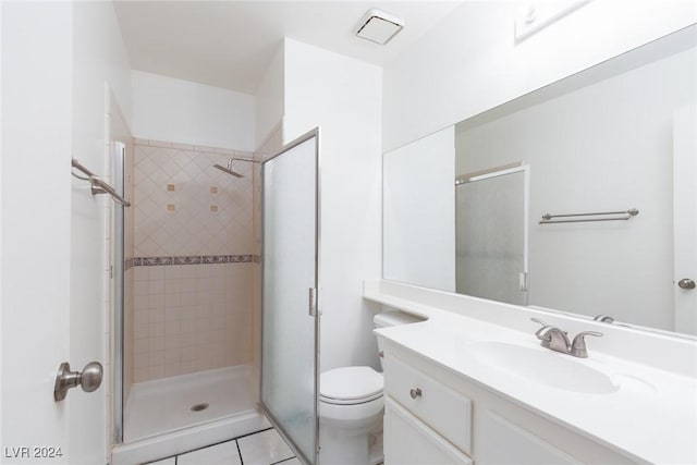 bathroom featuring vanity, tile patterned flooring, toilet, and walk in shower