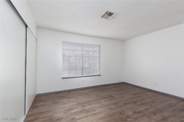 interior space with wood-type flooring, a textured ceiling, and a closet