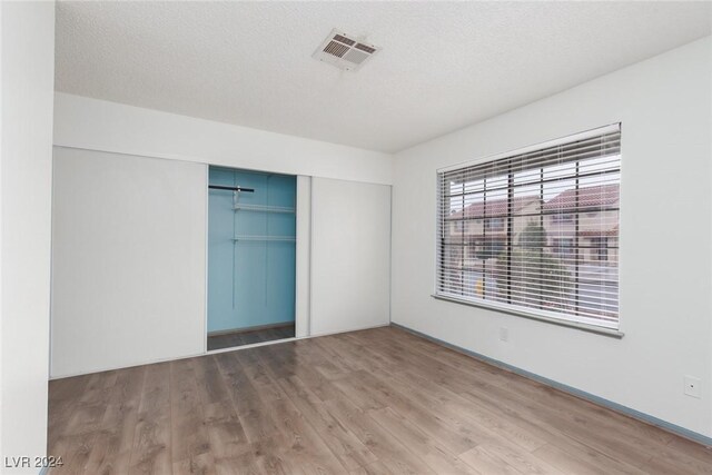 unfurnished bedroom with hardwood / wood-style floors, a closet, and a textured ceiling