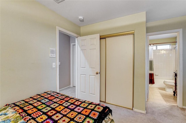 carpeted bedroom with ensuite bath and a closet