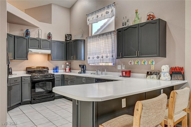 kitchen with black gas range oven, a breakfast bar area, gray cabinetry, and kitchen peninsula