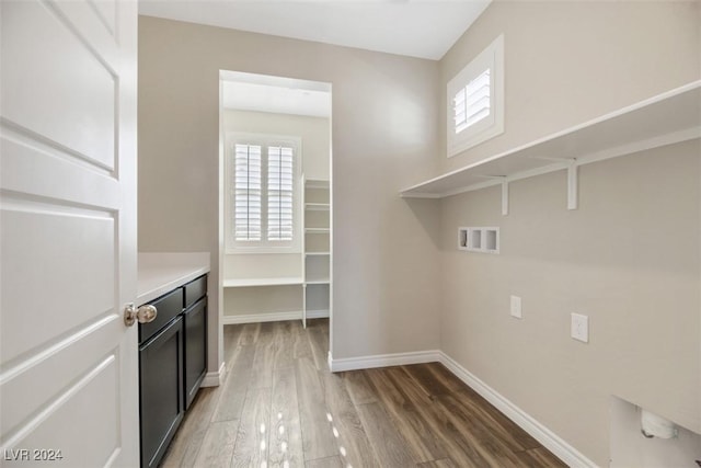 clothes washing area with hookup for a washing machine, baseboards, and wood finished floors