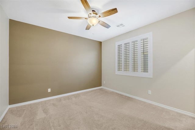 carpeted spare room featuring baseboards, visible vents, and ceiling fan