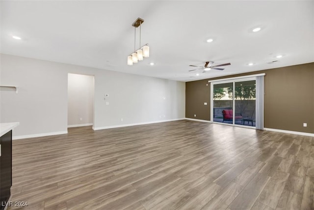 unfurnished living room with wood finished floors, baseboards, and ceiling fan