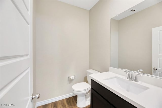 bathroom featuring vanity, wood finished floors, visible vents, baseboards, and toilet