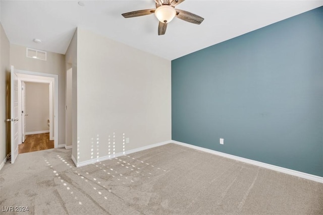 carpeted empty room with visible vents, baseboards, and a ceiling fan