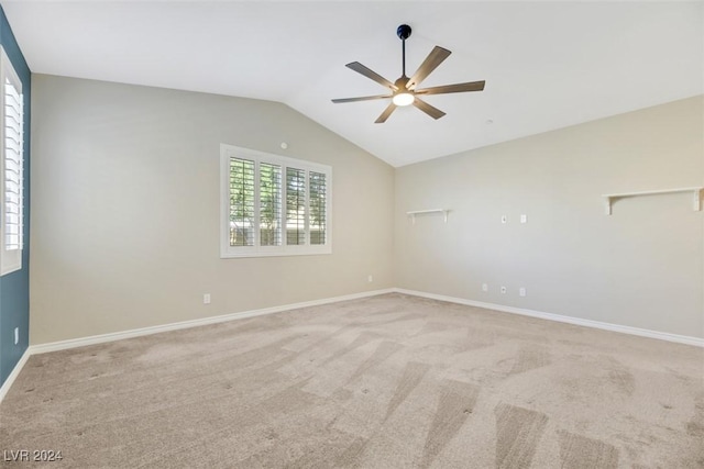 spare room with light carpet, ceiling fan, baseboards, and vaulted ceiling