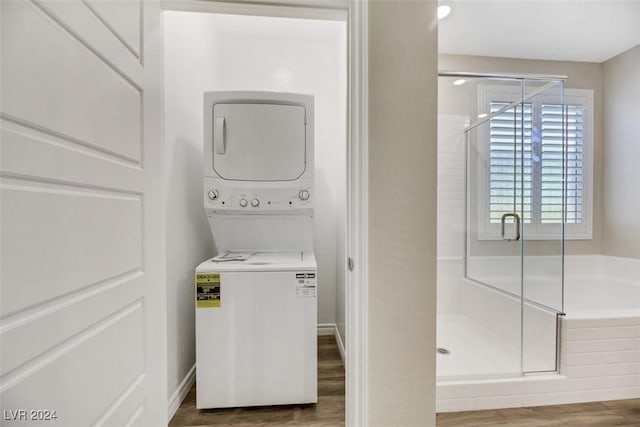 laundry room featuring stacked washer / drying machine, baseboards, and wood finished floors