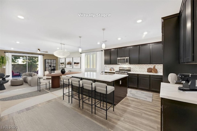 kitchen with a sink, stainless steel microwave, open floor plan, light countertops, and range