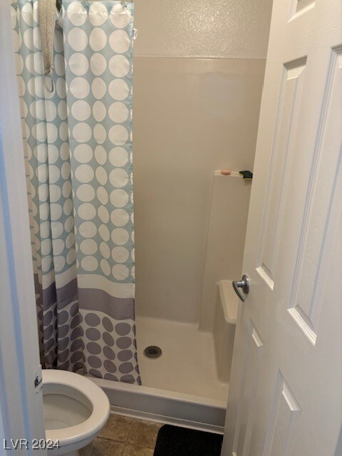 bathroom with tile patterned flooring, toilet, and walk in shower