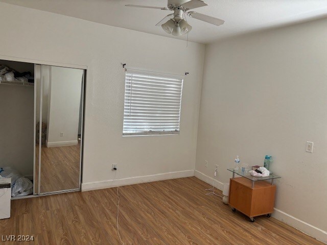 unfurnished bedroom featuring ceiling fan, a closet, and hardwood / wood-style flooring