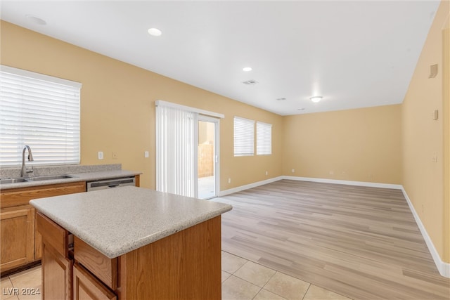 kitchen featuring light wood-type flooring, a kitchen island, stainless steel dishwasher, and sink