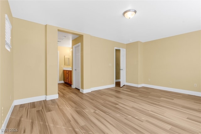 unfurnished bedroom with ensuite bathroom and light hardwood / wood-style flooring