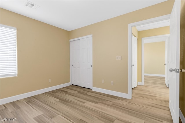 unfurnished bedroom with light wood-type flooring and a closet