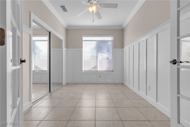 unfurnished room featuring ceiling fan, ornamental molding, and light tile patterned floors