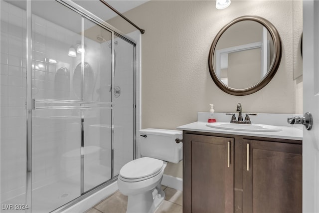 bathroom featuring tile patterned flooring, vanity, toilet, and walk in shower