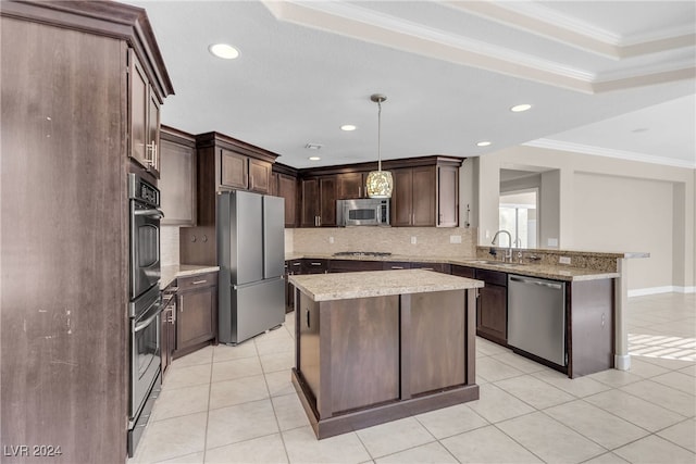 kitchen with appliances with stainless steel finishes, dark brown cabinets, sink, pendant lighting, and a kitchen island