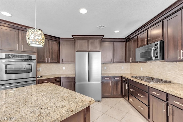 kitchen featuring pendant lighting, dark brown cabinets, backsplash, and appliances with stainless steel finishes