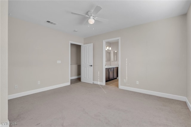 unfurnished bedroom featuring ensuite bathroom, ceiling fan, and light colored carpet