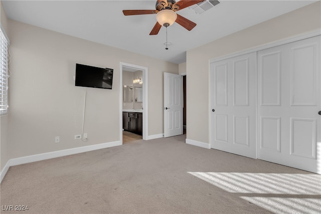 unfurnished bedroom with ceiling fan, ensuite bathroom, light carpet, and a closet