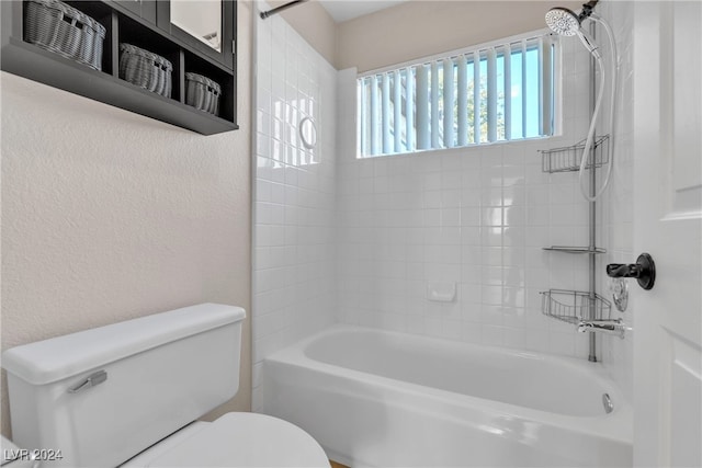 bathroom with toilet and tiled shower / bath