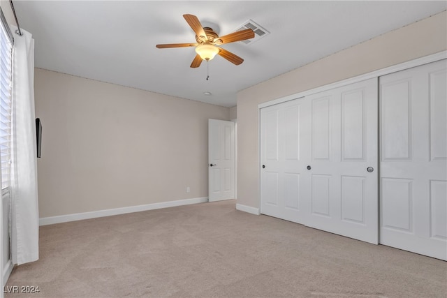 unfurnished bedroom featuring light carpet, a closet, and ceiling fan