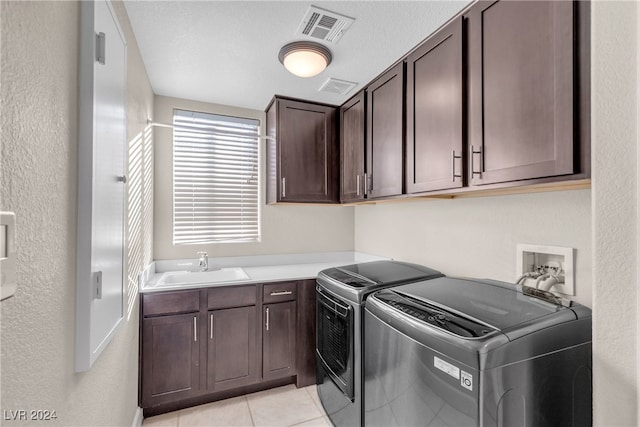 clothes washing area with cabinets, a textured ceiling, sink, separate washer and dryer, and light tile patterned flooring