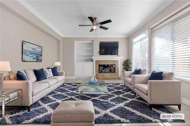 living room featuring built in shelves, ceiling fan, crown molding, a fireplace, and tile patterned flooring