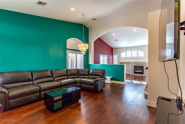 living room featuring a chandelier, dark wood-type flooring, vaulted ceiling, and a healthy amount of sunlight