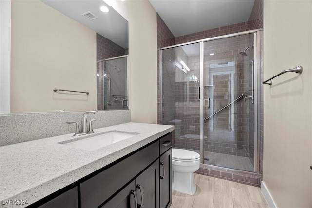 bathroom featuring hardwood / wood-style floors, vanity, toilet, and an enclosed shower