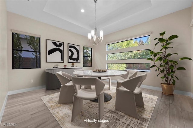 dining space featuring a tray ceiling, light hardwood / wood-style flooring, and a notable chandelier